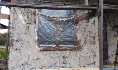 Окно затянуто полиэтиленовой пленкой, чтобы штукатурка не попадала на деревянные рамы и стекла