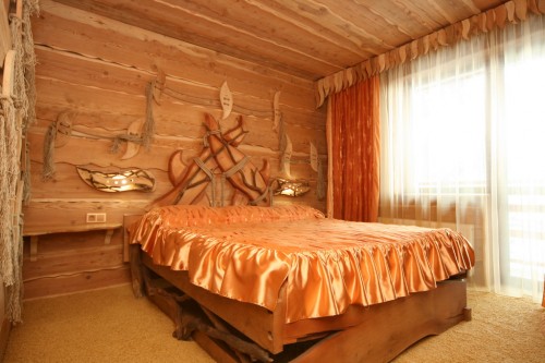 Широкая кровать, украшения из дерева на стенах